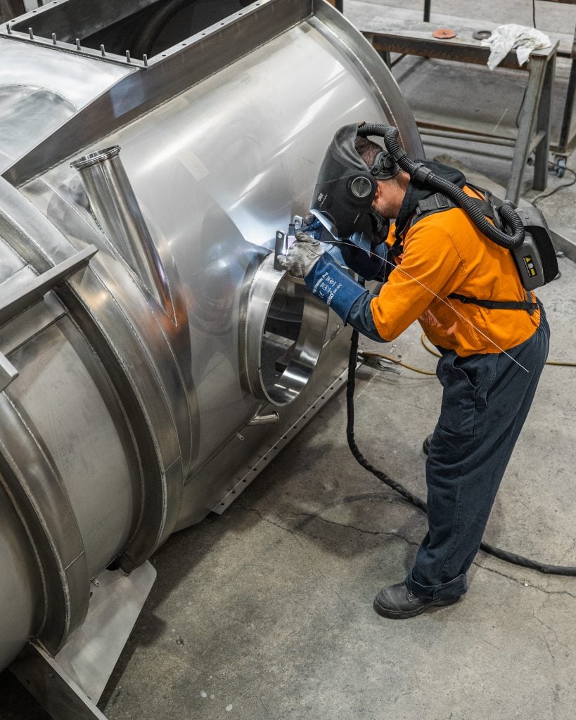 A fabricator works on a large product in Longveld's workshop